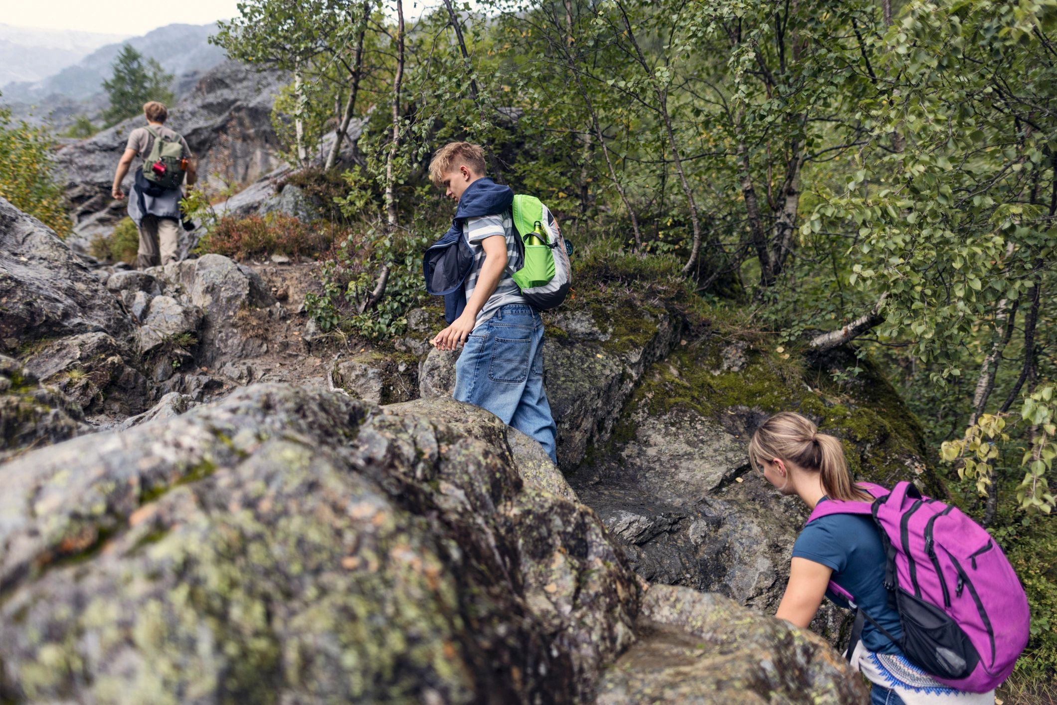 Hikers trekking on a rocky trail toward a glacier