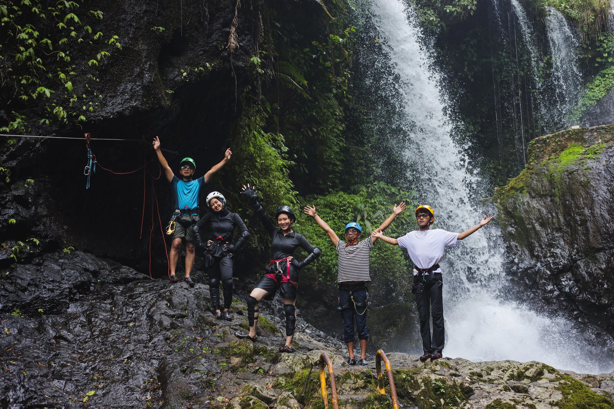 Friends cheering during a canyoning adventure near a waterfall