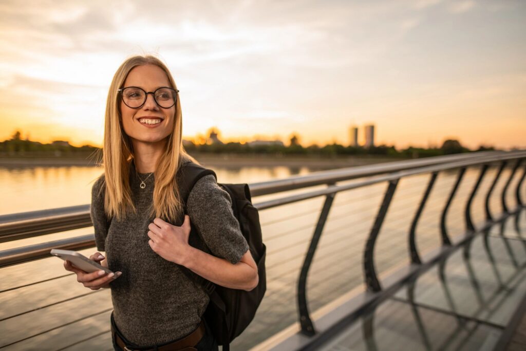 Happy young adult woman enjoying sunset on city bridge